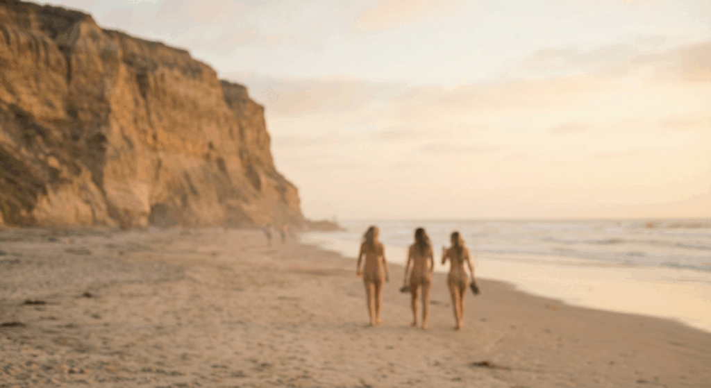 A photo of three women walking along the shoreline at Black's Beach in San Diego